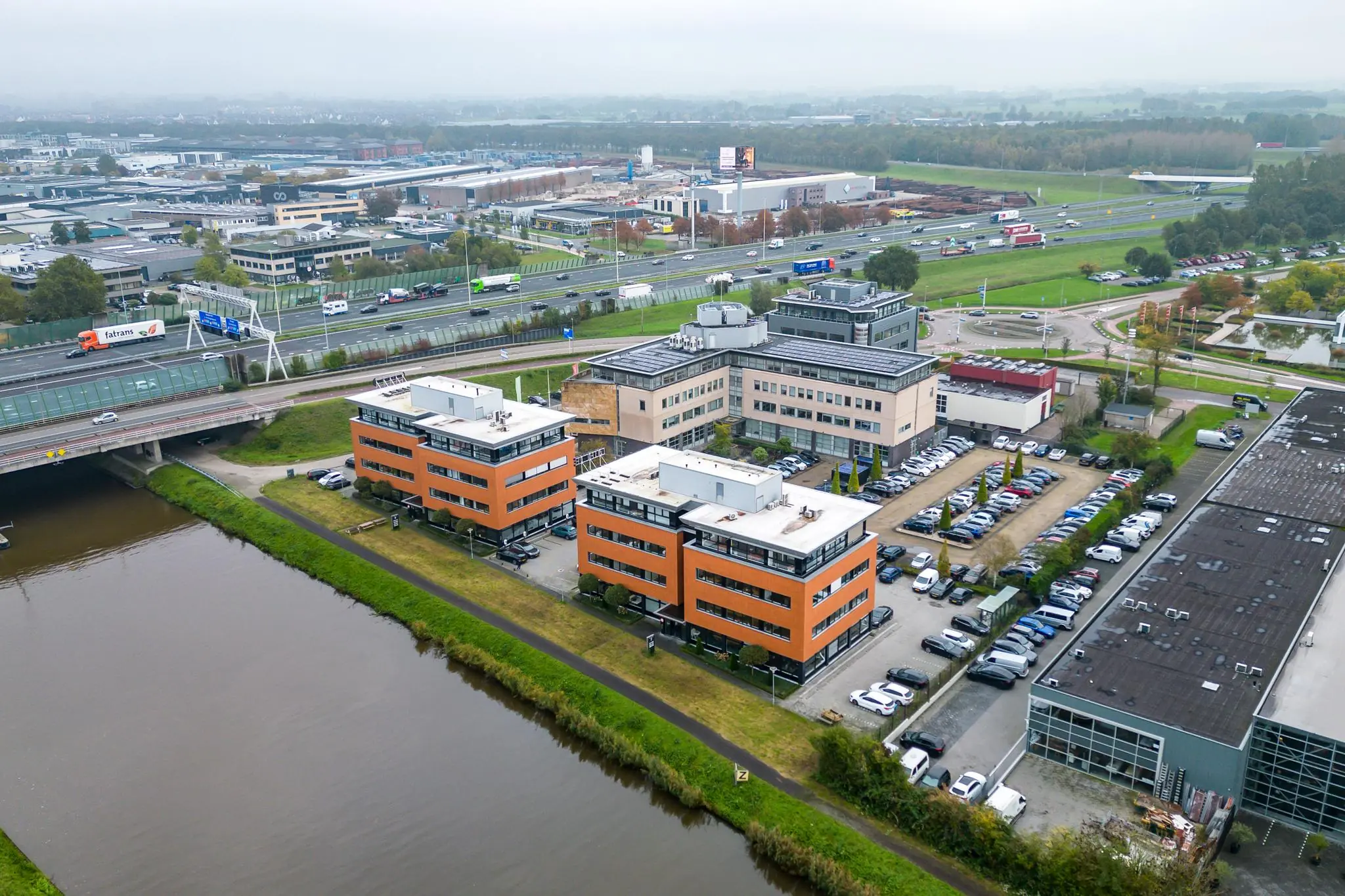 Luchtfoto van kantoorgebouwen aan de Lage Biezenweg in een bedrijventerrein langs de snelweg en een kanaal.